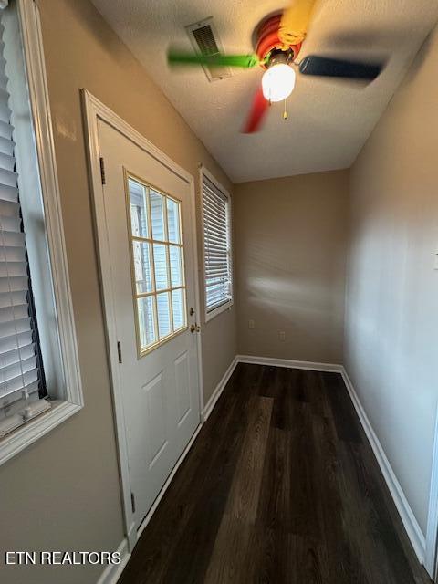 doorway to outside featuring dark wood-type flooring, ceiling fan, and a textured ceiling