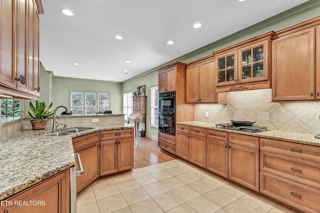 kitchen featuring sink, stainless steel gas cooktop, black double oven, light stone countertops, and backsplash