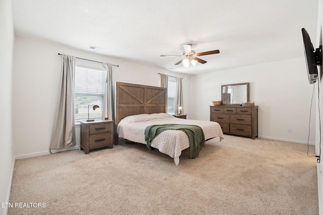 bedroom featuring light carpet, multiple windows, and ceiling fan