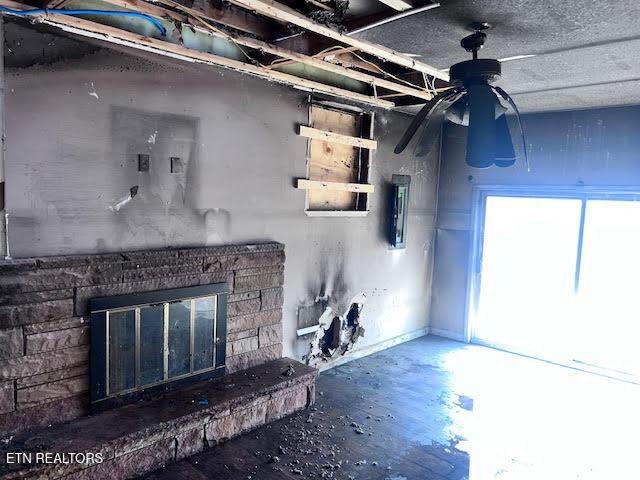 interior space with concrete flooring, a stone fireplace, and ceiling fan