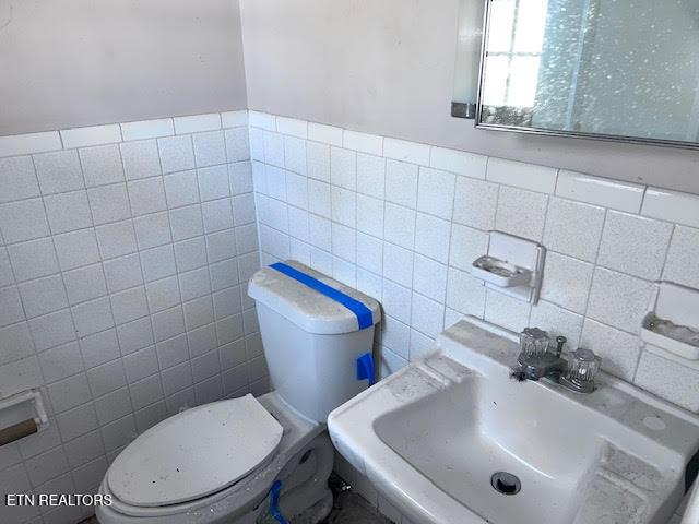 bathroom with sink, tile walls, and toilet