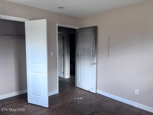 unfurnished bedroom featuring dark hardwood / wood-style floors and a closet