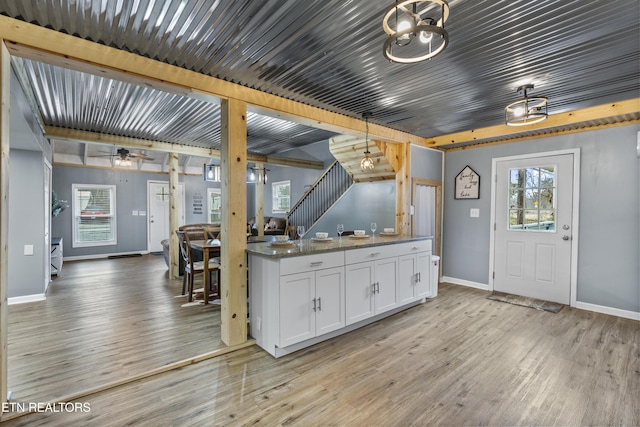 kitchen with ceiling fan, hanging light fixtures, light stone countertops, white cabinets, and light wood-type flooring