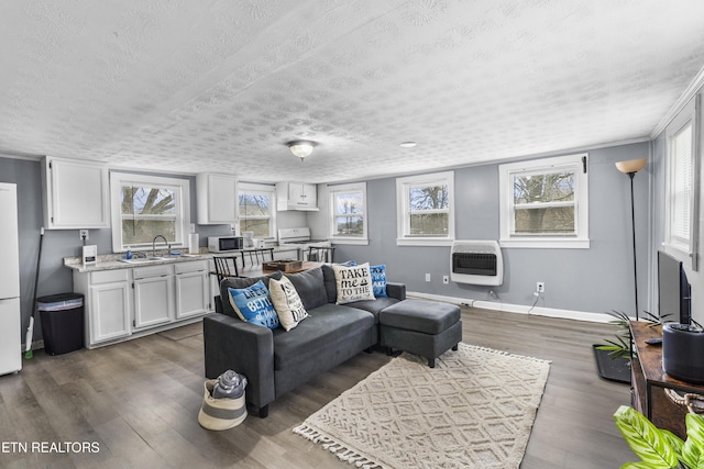 living room with sink, heating unit, a textured ceiling, and dark hardwood / wood-style floors