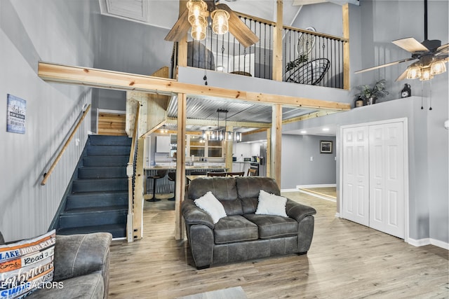 living room featuring a towering ceiling, light hardwood / wood-style flooring, and ceiling fan