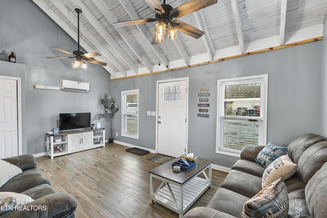 living room with hardwood / wood-style floors, plenty of natural light, a wall mounted air conditioner, and beamed ceiling