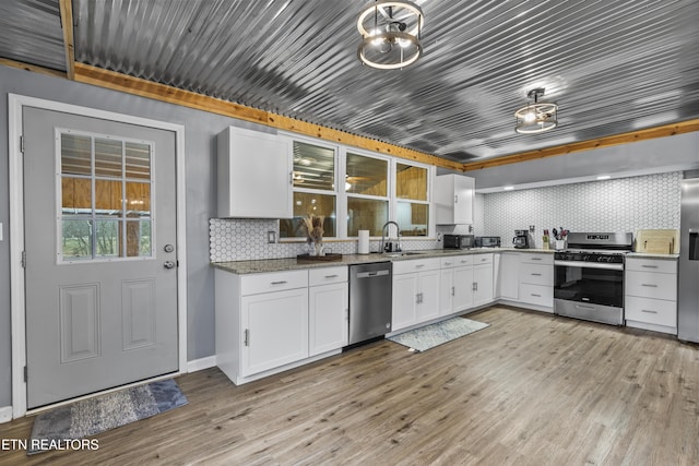 kitchen featuring sink, appliances with stainless steel finishes, white cabinetry, decorative backsplash, and light wood-type flooring