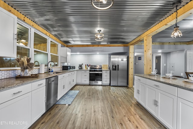 kitchen featuring white cabinetry, stainless steel appliances, and hanging light fixtures