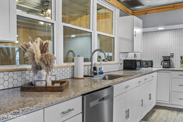 kitchen featuring white cabinetry, light stone countertops, and stainless steel dishwasher