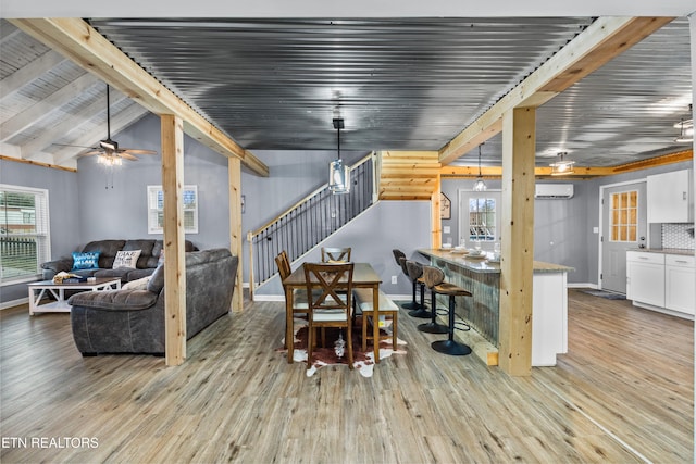 dining space with vaulted ceiling with beams, a wall unit AC, light hardwood / wood-style floors, and ceiling fan