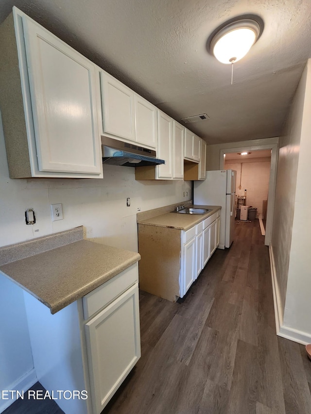 kitchen featuring sink, a textured ceiling, white refrigerator, dark hardwood / wood-style flooring, and white cabinets