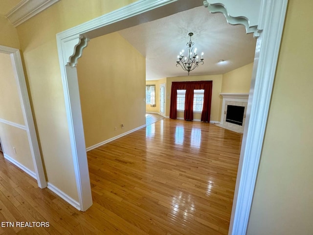 unfurnished living room featuring an inviting chandelier, light hardwood / wood-style floors, and a tiled fireplace