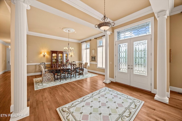 entryway featuring a notable chandelier, crown molding, decorative columns, and hardwood / wood-style flooring