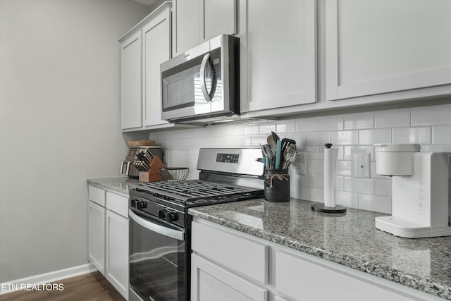 kitchen with tasteful backsplash, white cabinets, dark hardwood / wood-style flooring, stainless steel appliances, and light stone countertops