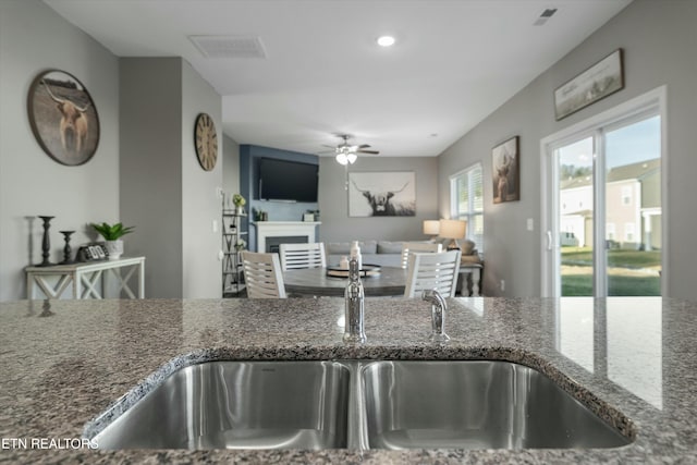 kitchen with ceiling fan, sink, and dark stone countertops