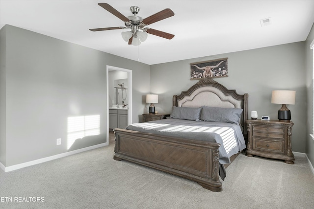 bedroom featuring ensuite bathroom, light colored carpet, and ceiling fan