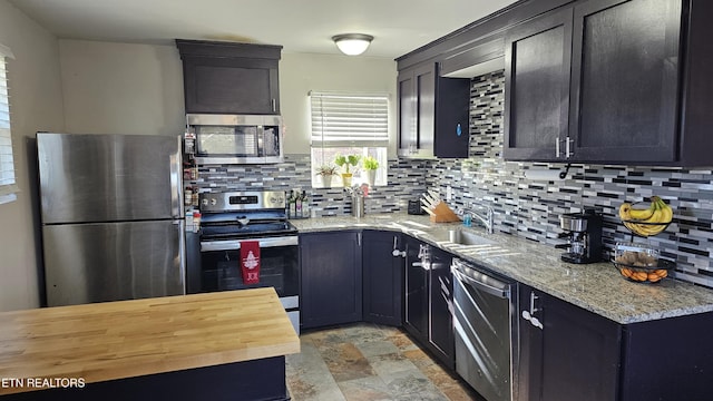 kitchen featuring sink, backsplash, light stone countertops, and appliances with stainless steel finishes