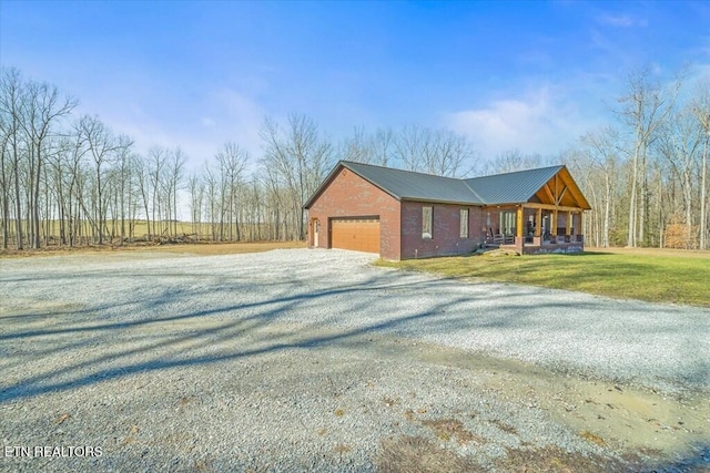 view of side of home featuring a garage, covered porch, and a lawn