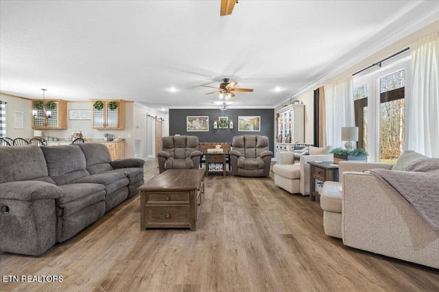 living room featuring crown molding, light hardwood / wood-style flooring, and ceiling fan