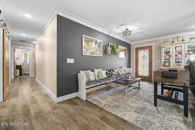 living room with hardwood / wood-style flooring, a barn door, and crown molding