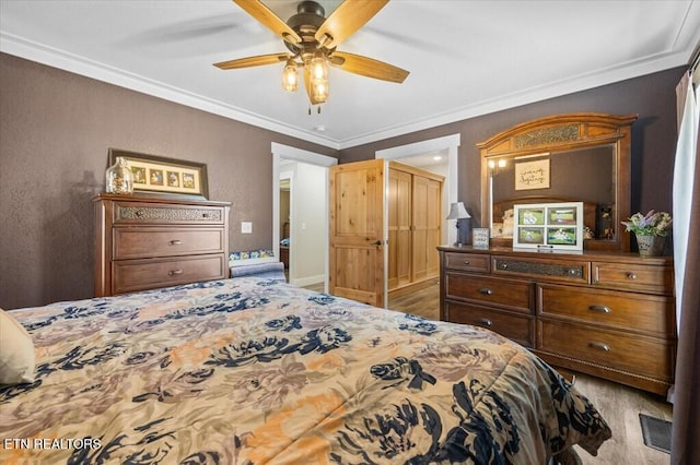 bedroom with ornamental molding, hardwood / wood-style floors, ceiling fan, and a closet