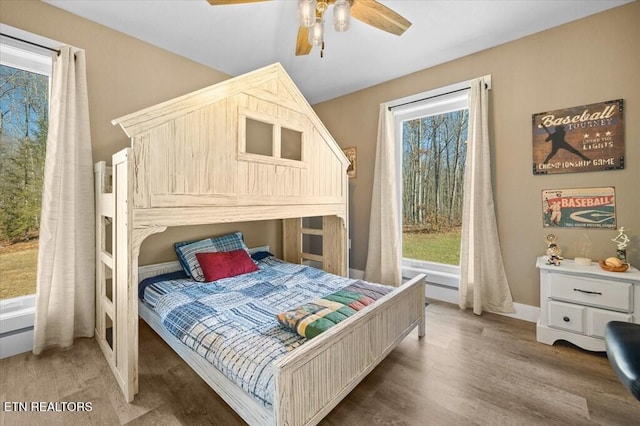 bedroom with multiple windows, dark wood-type flooring, and ceiling fan