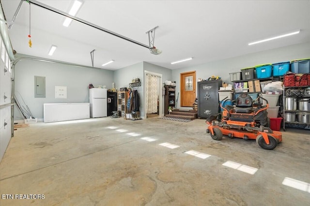 garage featuring a garage door opener, white fridge, and electric panel