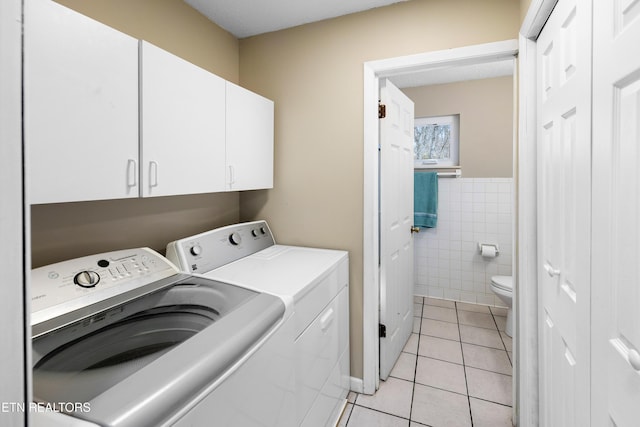 laundry room featuring cabinets, light tile patterned flooring, washer and dryer, and tile walls