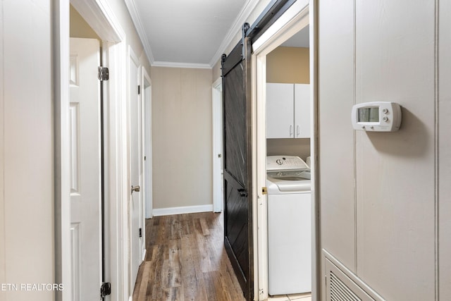 hall with a barn door, ornamental molding, washer / dryer, and hardwood / wood-style flooring