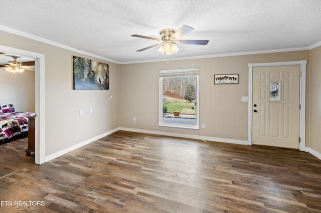 foyer featuring ceiling fan, dark wood-type flooring, ornamental molding, and a textured ceiling