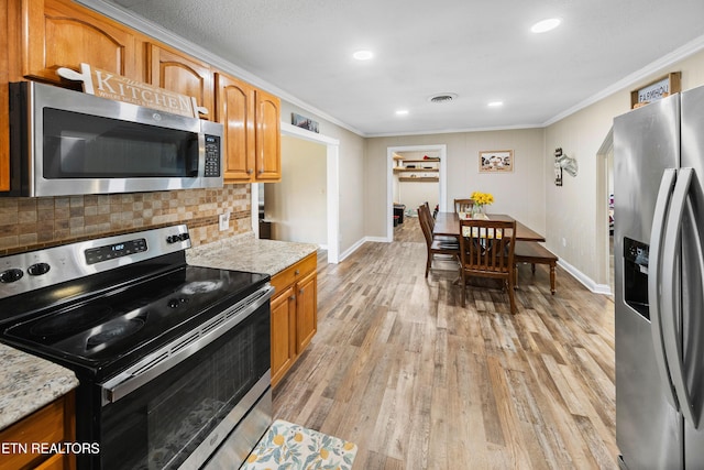 kitchen with stainless steel appliances, crown molding, light stone countertops, and light hardwood / wood-style floors