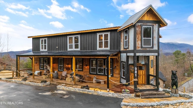 view of front facade featuring metal roof, a porch, board and batten siding, and a mountain view