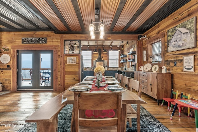 dining area with light wood-style floors, wood ceiling, wooden walls, and french doors