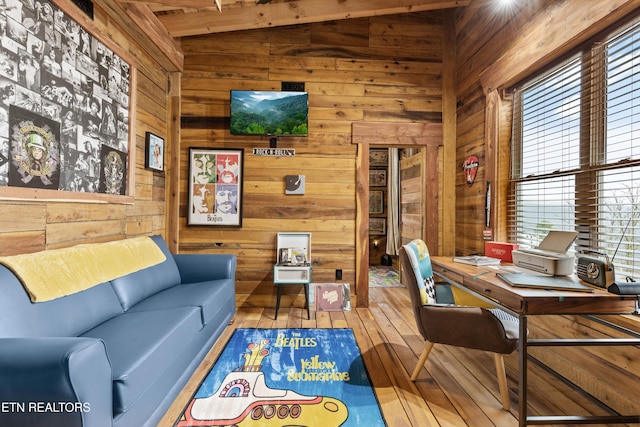 living area with vaulted ceiling, wood finished floors, and wooden walls