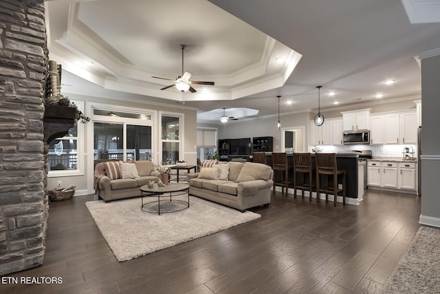 living room with crown molding, ceiling fan, a tray ceiling, and dark hardwood / wood-style flooring