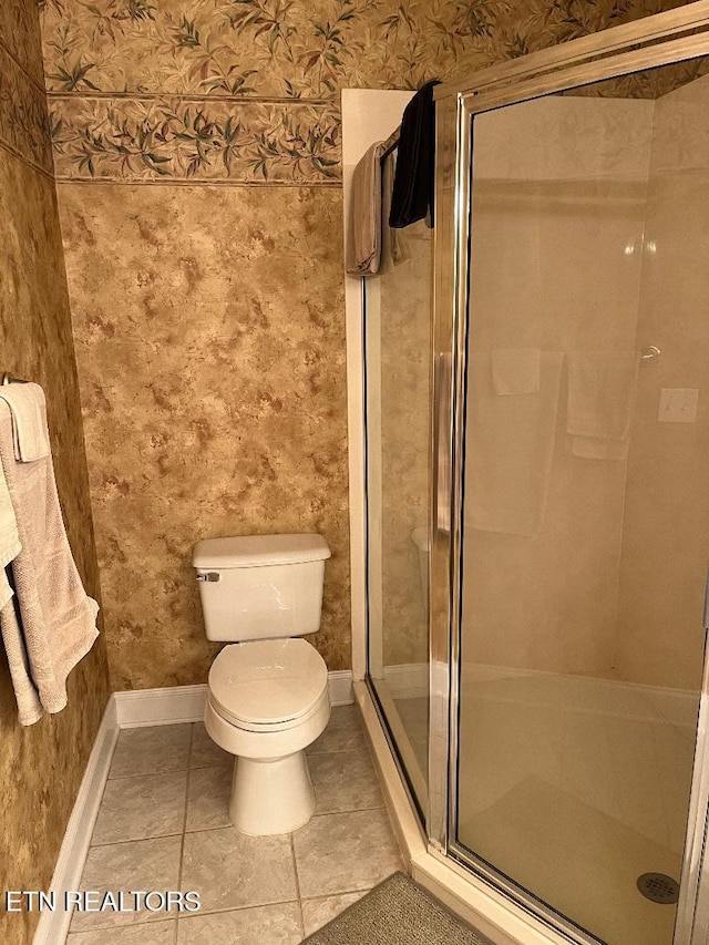 bathroom with tile patterned floors, toilet, and a shower with shower door