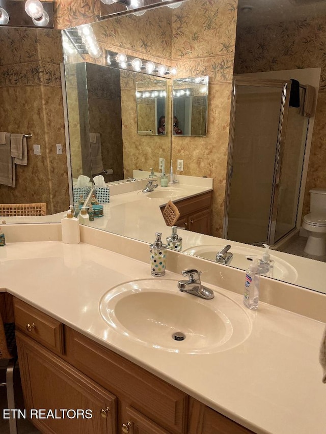 bathroom featuring vanity, toilet, and a shower with shower door