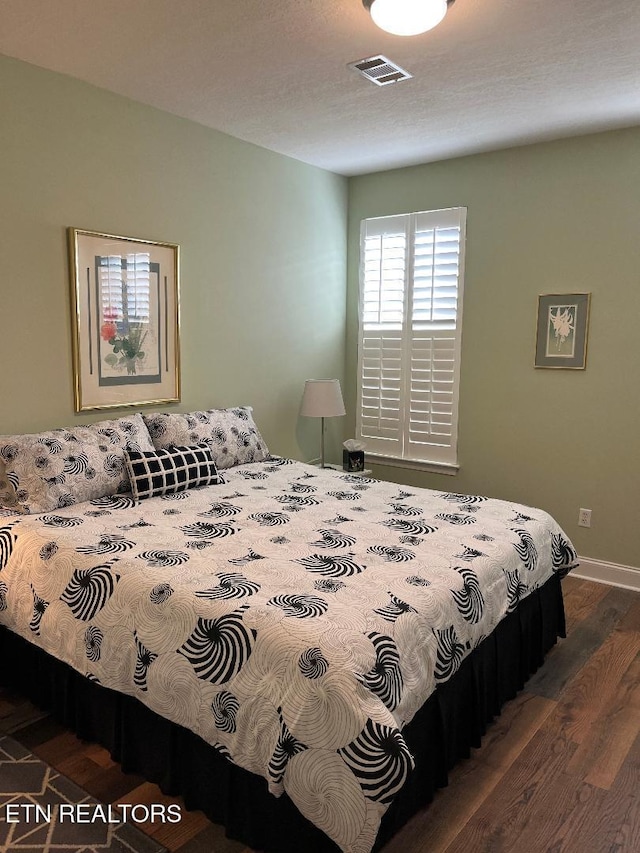 bedroom featuring wood finished floors, visible vents, and baseboards