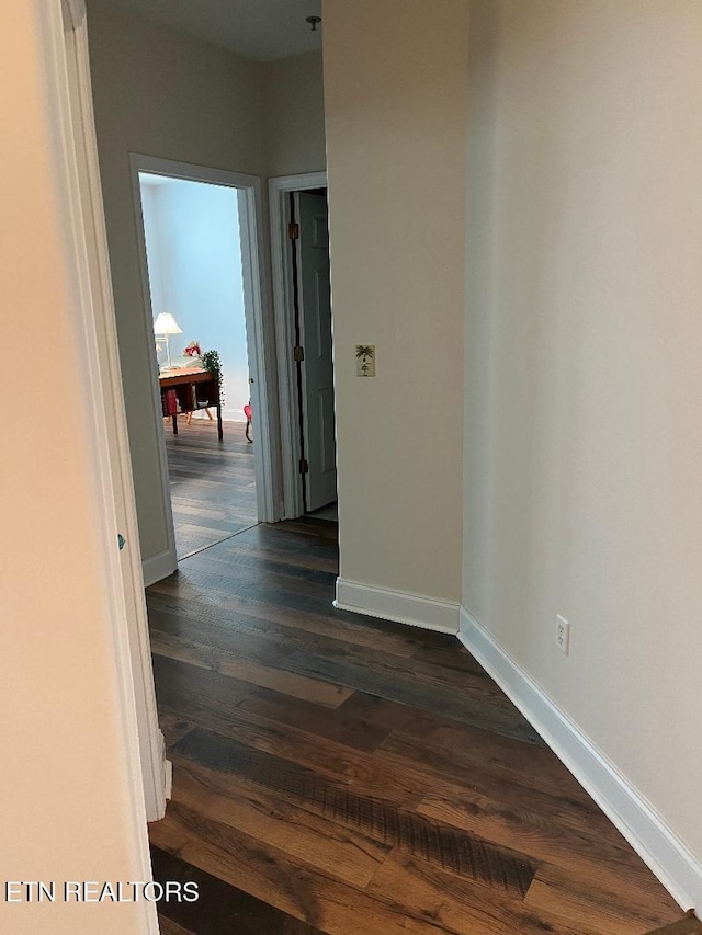 hallway featuring dark wood-style floors and baseboards