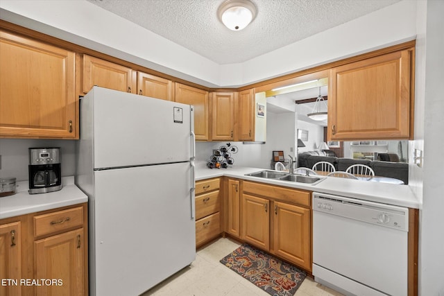 kitchen with brown cabinetry, white appliances, light countertops, and a sink