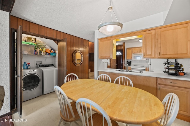 dining space with a textured ceiling, light floors, separate washer and dryer, and wood walls