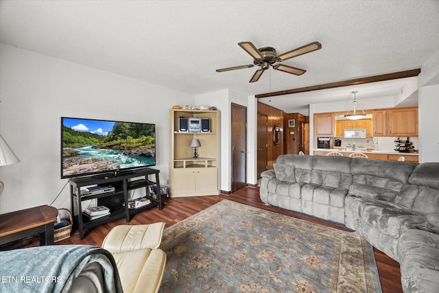 living room featuring a textured ceiling, ceiling fan, and dark wood-style flooring