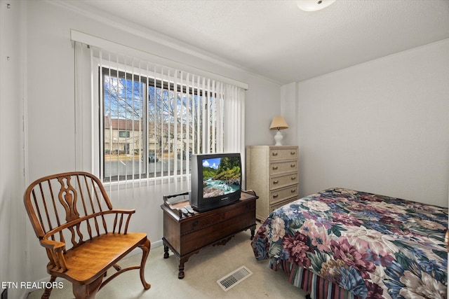 bedroom featuring carpet floors, visible vents, and a textured ceiling