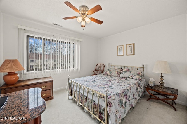 bedroom with light carpet, ceiling fan, visible vents, and baseboards