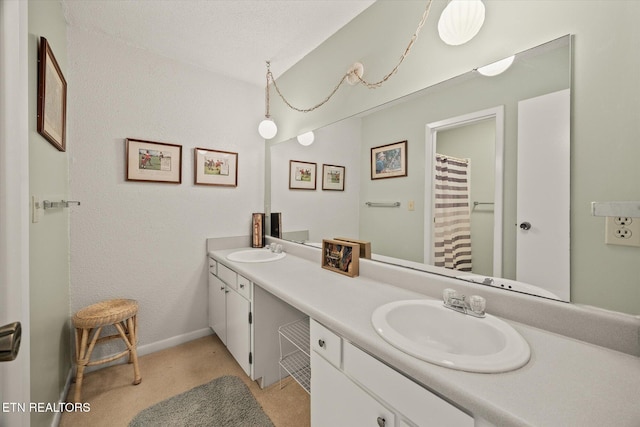 full bathroom featuring double vanity, a sink, and baseboards