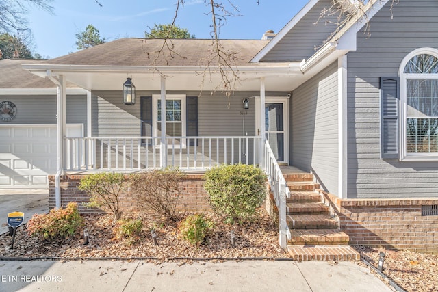 view of exterior entry with a garage and covered porch