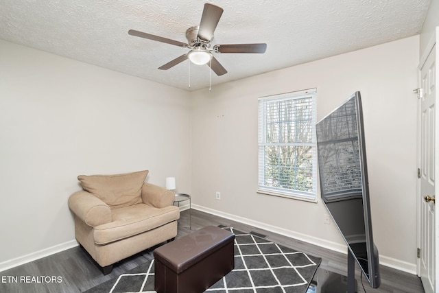 living area with ceiling fan, dark hardwood / wood-style floors, and a textured ceiling