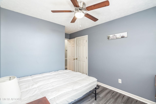 bedroom featuring ceiling fan, wood-type flooring, and a textured ceiling