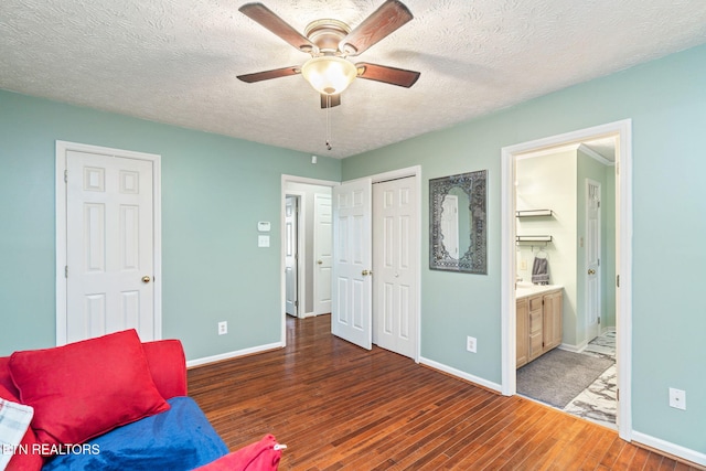 living area featuring ceiling fan, dark hardwood / wood-style flooring, and a textured ceiling