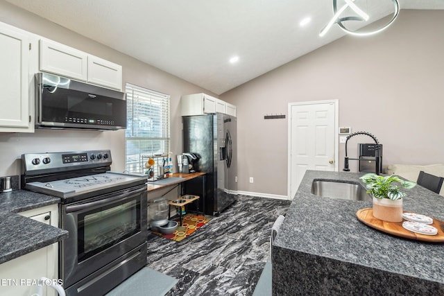 kitchen with sink, dark stone countertops, stainless steel appliances, white cabinets, and vaulted ceiling